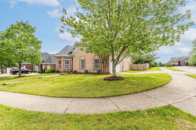 view of front of home featuring fence, a front yard, and brick siding