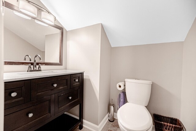 bathroom with vanity, baseboards, toilet, and lofted ceiling