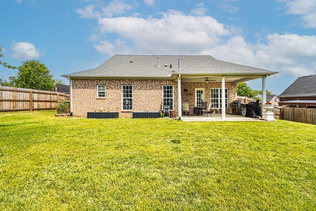 rear view of property featuring a patio, a fenced backyard, brick siding, a ceiling fan, and a lawn
