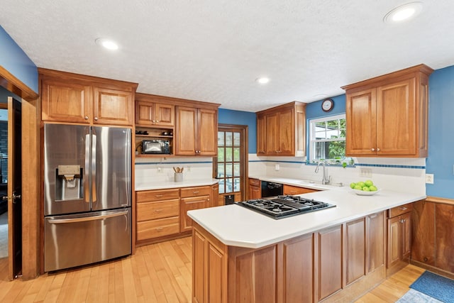319 Powder Mill Dr, Ashland City, TN 37015 - kitchen featuring a sink, light countertops, light wood-style flooring, a peninsula, and black appliances