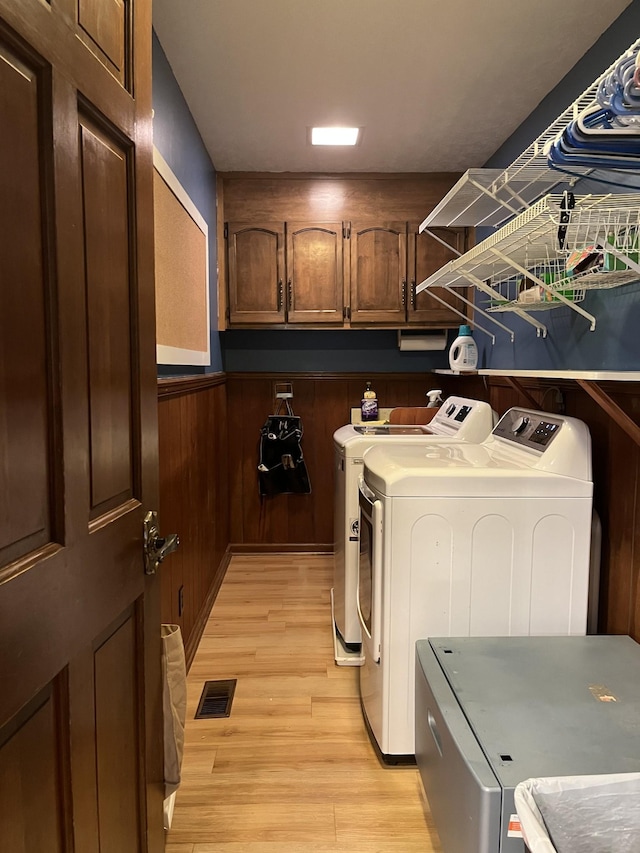 319 Powder Mill Dr, Ashland City, TN 37015 - laundry area with visible vents, washing machine and clothes dryer, light wood-type flooring, cabinet space, and a wainscoted wall