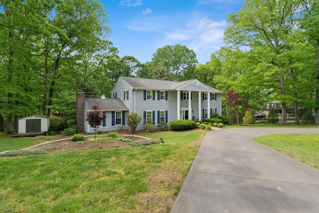 319 Powder Mill Dr, Ashland City, TN 37015 - neoclassical home featuring a chimney, a front yard, an outbuilding, a storage unit, and concrete driveway