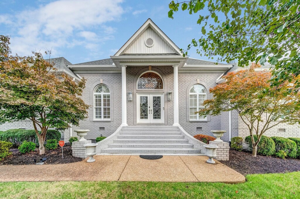 doorway to property featuring french doors, board and batten siding, roof with shingles, and brick siding