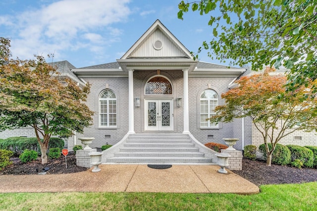 doorway to property featuring french doors, board and batten siding, roof with shingles, and brick siding