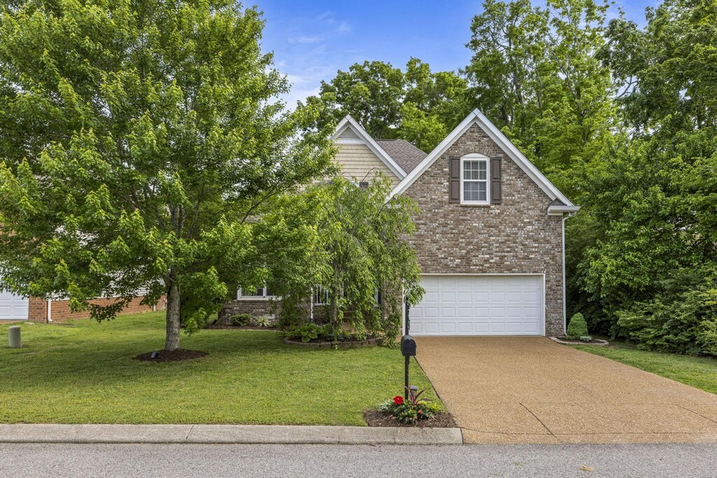 obstructed view of property featuring brick siding, an attached garage, driveway, and a front lawn