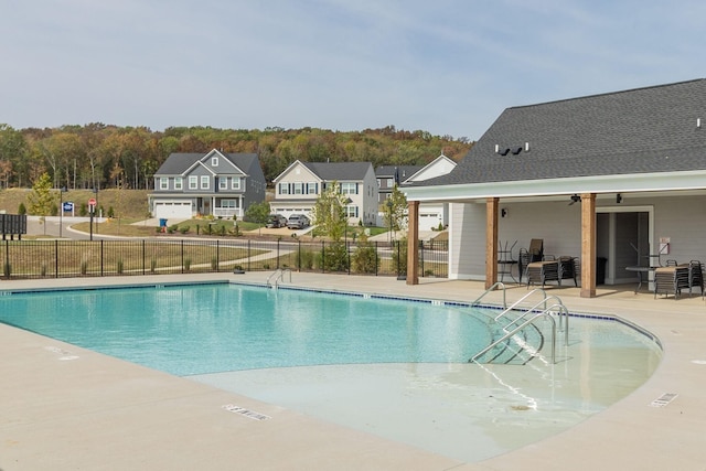 community pool with fence, a patio area, and a residential view