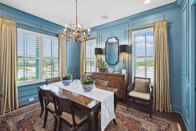 dining area with baseboards, a notable chandelier, a wealth of natural light, and a decorative wall