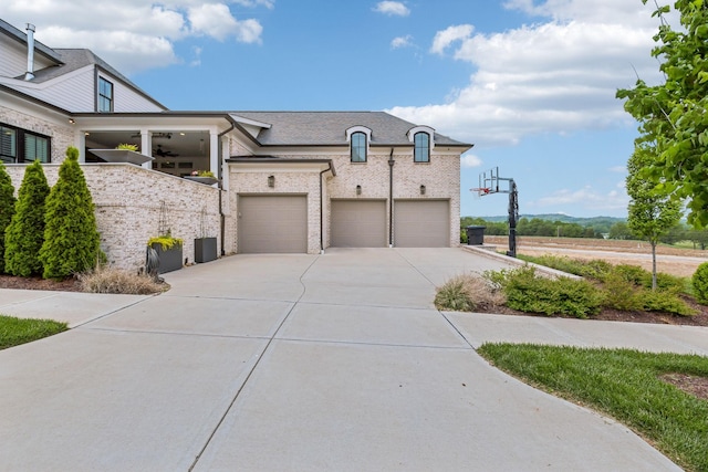 view of front of property with a garage, a ceiling fan, driveway, and brick siding