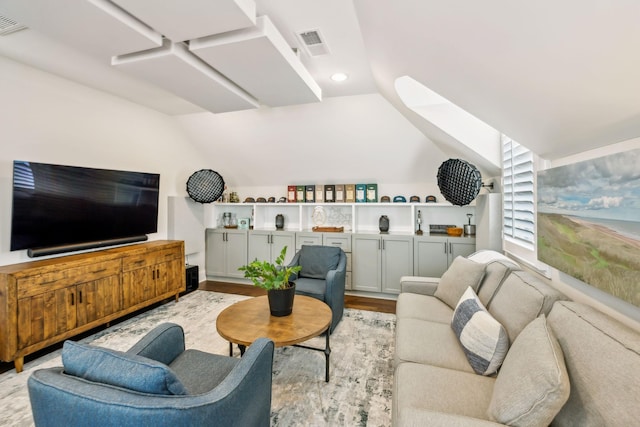 living area with visible vents, light wood-style floors, indoor bar, recessed lighting, and vaulted ceiling