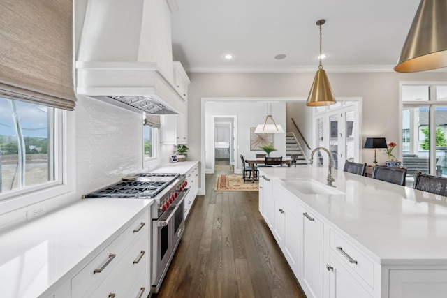 kitchen with a sink, light countertops, double oven range, custom range hood, and backsplash