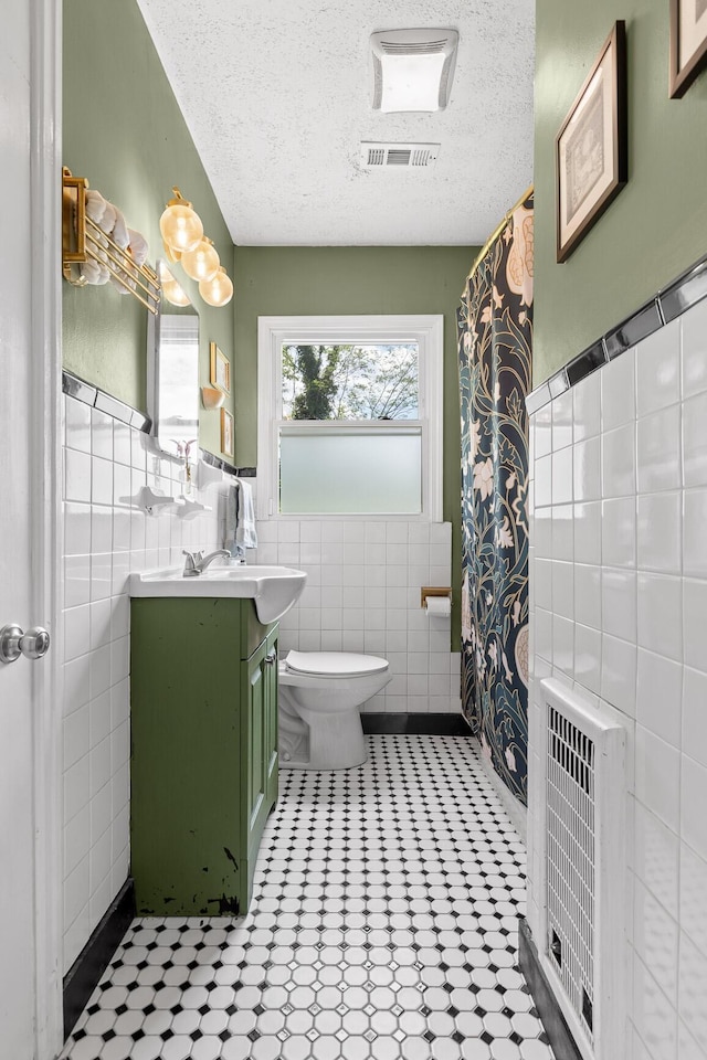 3610 Gleason Dr, Chattanooga, TN 37412 - full bathroom with visible vents, vanity, toilet, tile walls, and a textured ceiling