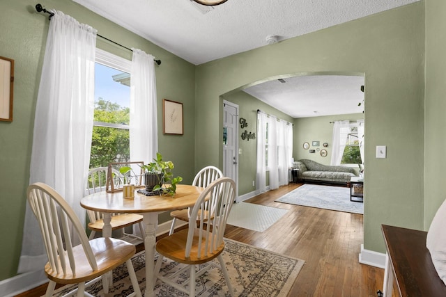 3610 Gleason Dr, Chattanooga, TN 37412 - dining space featuring arched walkways, baseboards, a textured ceiling, and light wood-style flooring