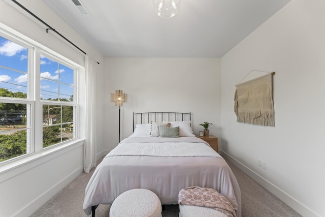 carpeted bedroom featuring baseboards, visible vents, and multiple windows
