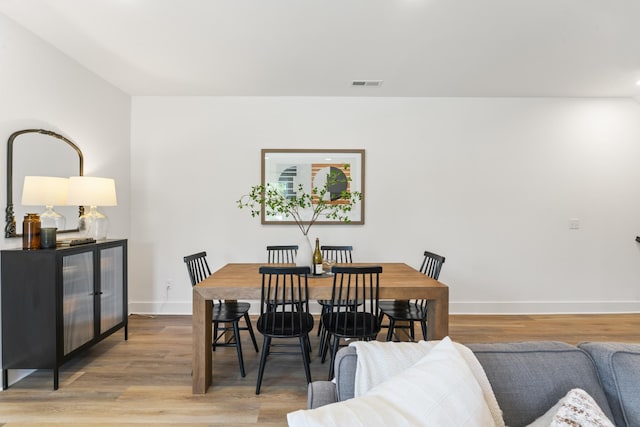 dining space with baseboards, light wood finished floors, and visible vents
