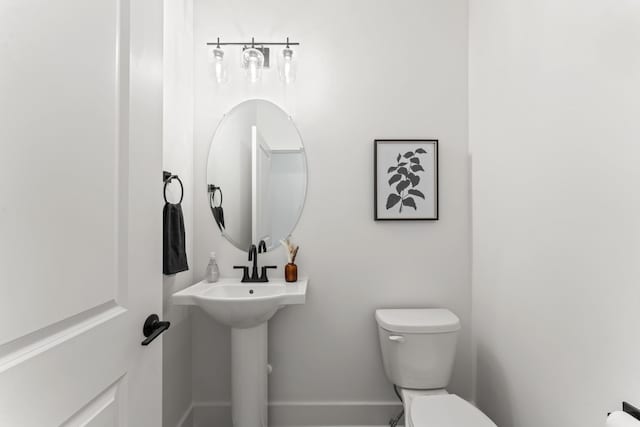 half bath with baseboards and toilet