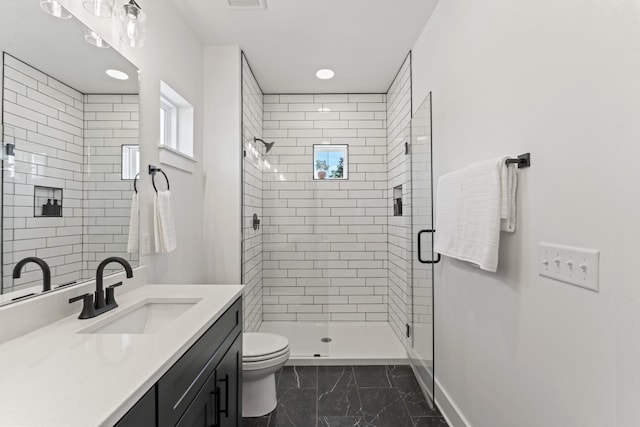 full bathroom featuring vanity, toilet, marble finish floor, baseboards, and a stall shower
