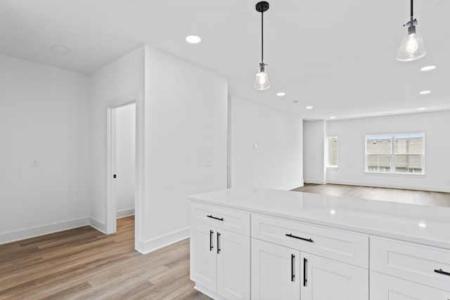 kitchen with light wood-type flooring, white cabinetry, baseboards, and decorative light fixtures