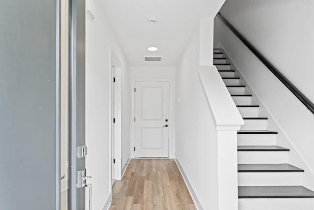 corridor with stairs, baseboards, visible vents, and light wood-style floors