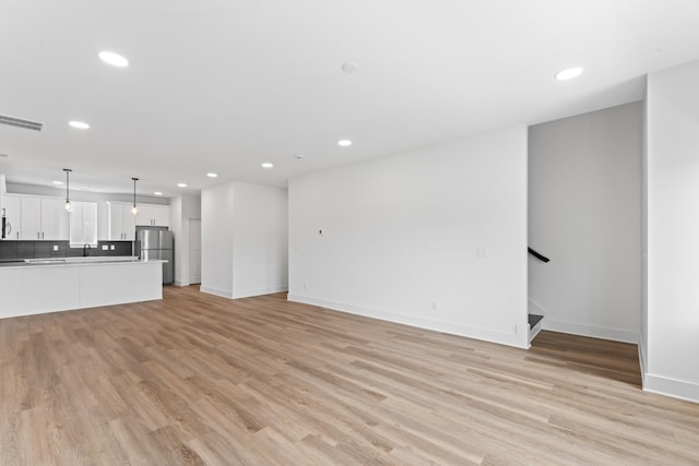 unfurnished living room featuring visible vents, stairs, baseboards, recessed lighting, and light wood-style flooring