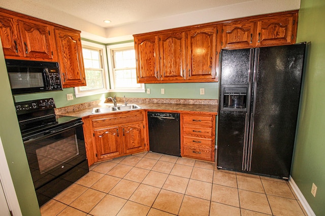 kitchen featuring light tile patterned flooring, brown cabinetry, a sink, and black appliances