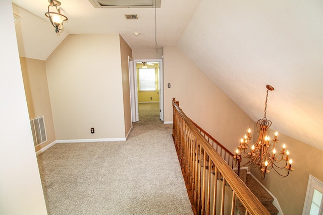 hall with visible vents, light colored carpet, vaulted ceiling, baseboards, and an upstairs landing