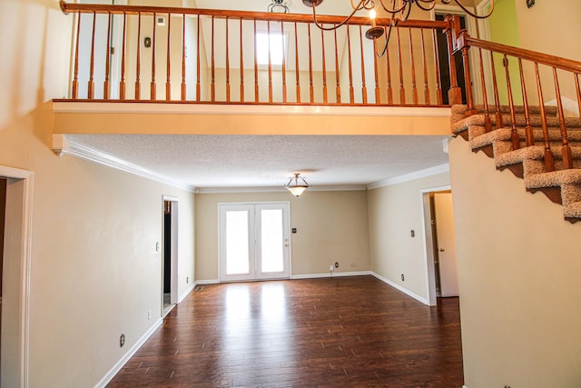 interior space with crown molding, a notable chandelier, a textured ceiling, hardwood / wood-style floors, and stairway