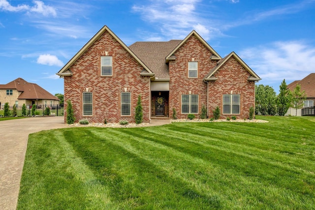 view of front facade featuring fence, a front lawn, and brick siding