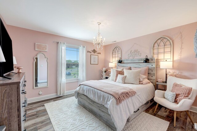 bedroom with baseboards, wood finished floors, and a chandelier