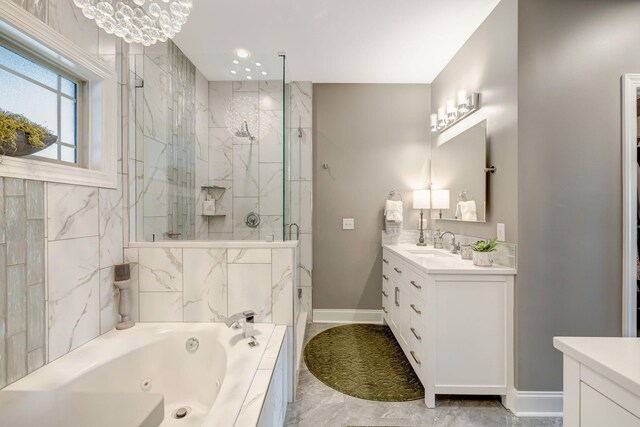 full bathroom featuring a marble finish shower, baseboards, vanity, and a tub with jets