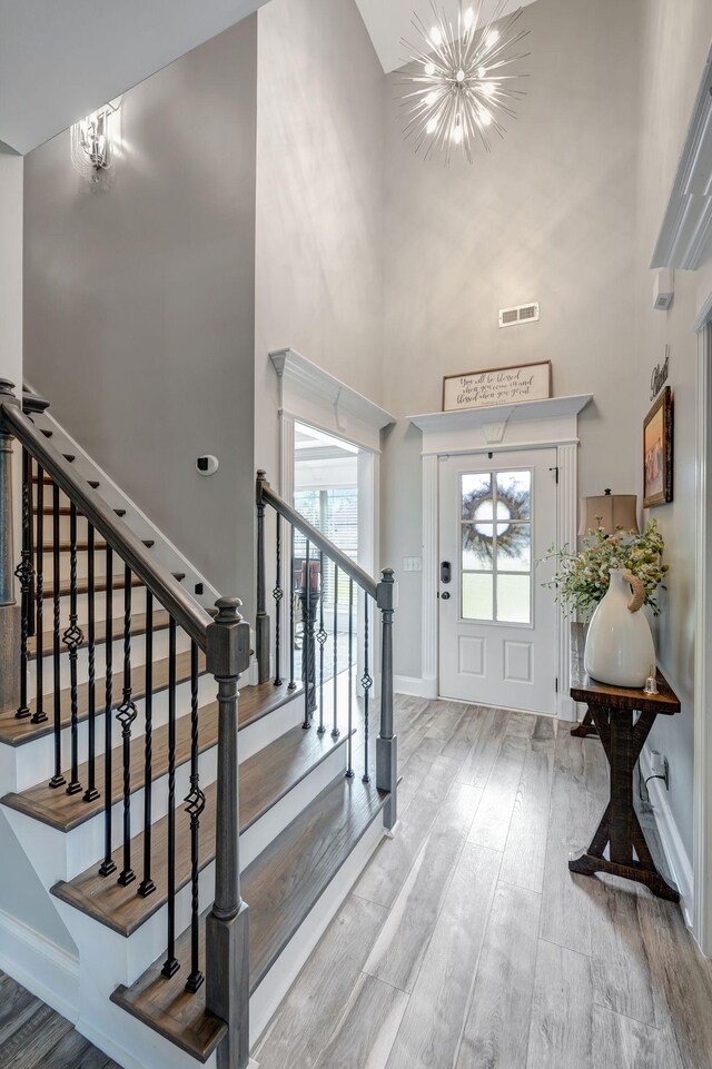 foyer with an inviting chandelier, a high ceiling, stairs, and visible vents