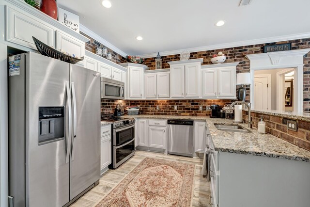 kitchen with decorative backsplash, crown molding, a sink, stainless steel appliances, and white cabinetry