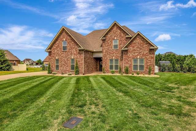 view of front facade featuring brick siding, a shingled roof, and a front lawn