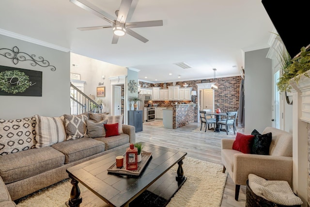 living area featuring brick wall, ornamental molding, ceiling fan, and light wood-style flooring