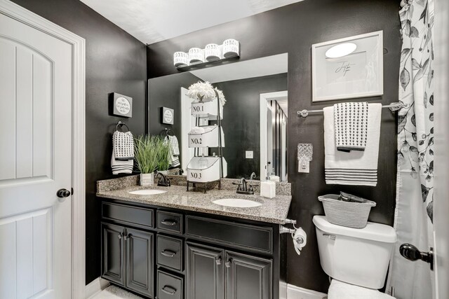 full bath with double vanity, toilet, and a sink