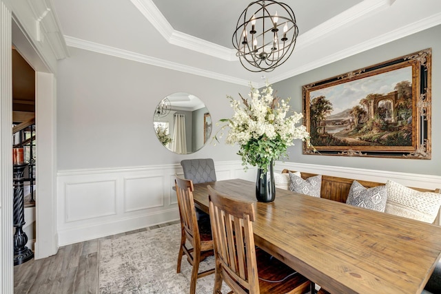 dining room with crown molding, wainscoting, wood finished floors, a chandelier, and arched walkways