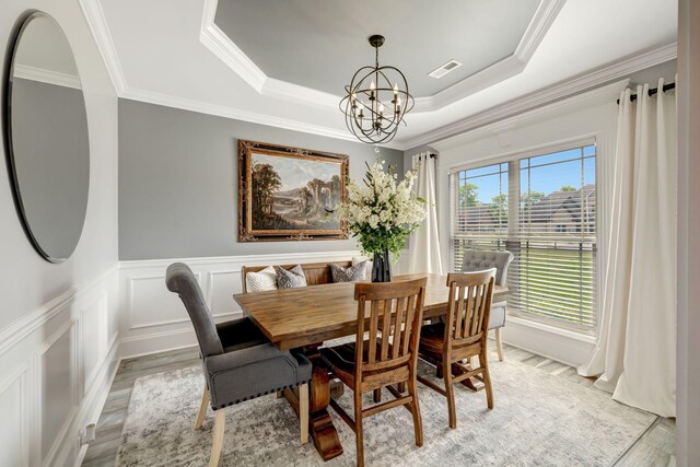 dining area featuring an inviting chandelier, crown molding, light wood-style flooring, and visible vents