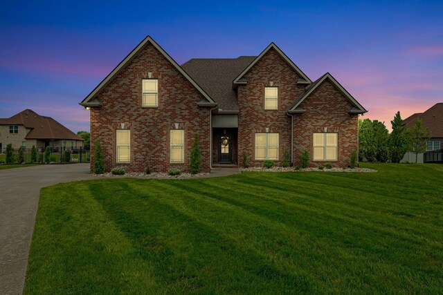 traditional-style house featuring a yard, brick siding, and fence