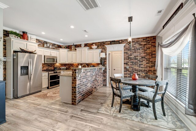 kitchen with crown molding, stainless steel appliances, light wood finished floors, and visible vents