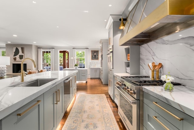 208 Carden Ave, Nashville, TN 37205 - kitchen with exhaust hood, appliances with stainless steel finishes, light stone countertops, a sink, and light wood-style flooring