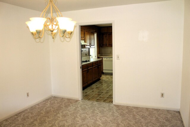 unfurnished dining area featuring an inviting chandelier, carpet floors, and baseboards