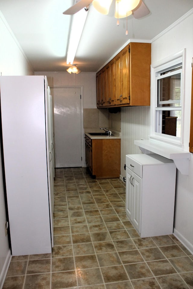 kitchen featuring brown cabinets, ceiling fan, a sink, light countertops, and freestanding refrigerator