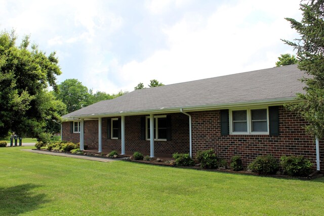 ranch-style house with brick siding, a front lawn, and roof with shingles