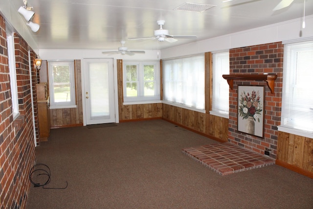 unfurnished sunroom with visible vents, brick wall, baseboards, wooden walls, and carpet flooring
