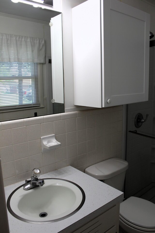 bathroom with toilet, tile walls, decorative backsplash, and vanity