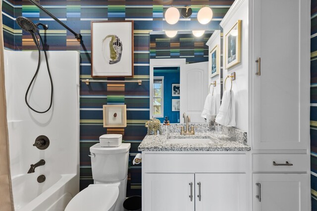 bathroom with vanity, shower / tub combination, toilet, and wallpapered walls
