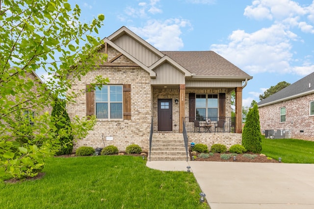 craftsman house with board and batten siding, a porch, brick siding, and a front yard