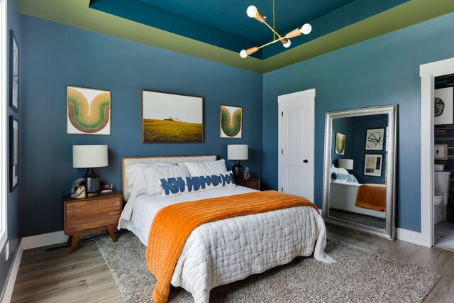 bedroom featuring baseboards, wood finished floors, and a notable chandelier