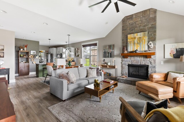 living room with a fireplace, a ceiling fan, baseboards, wood finished floors, and lofted ceiling