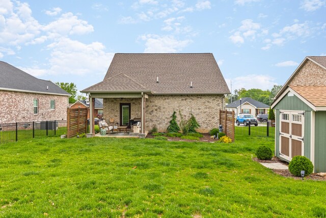 rear view of property with a patio, a fenced backyard, a yard, and brick siding