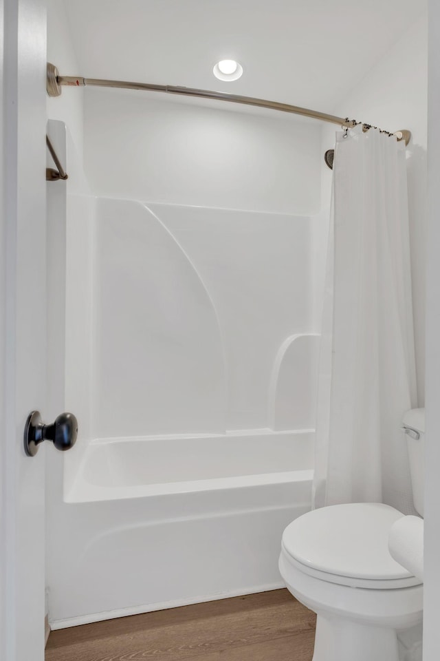 bathroom with wood finished floors, shower / bath combination with curtain, and toilet